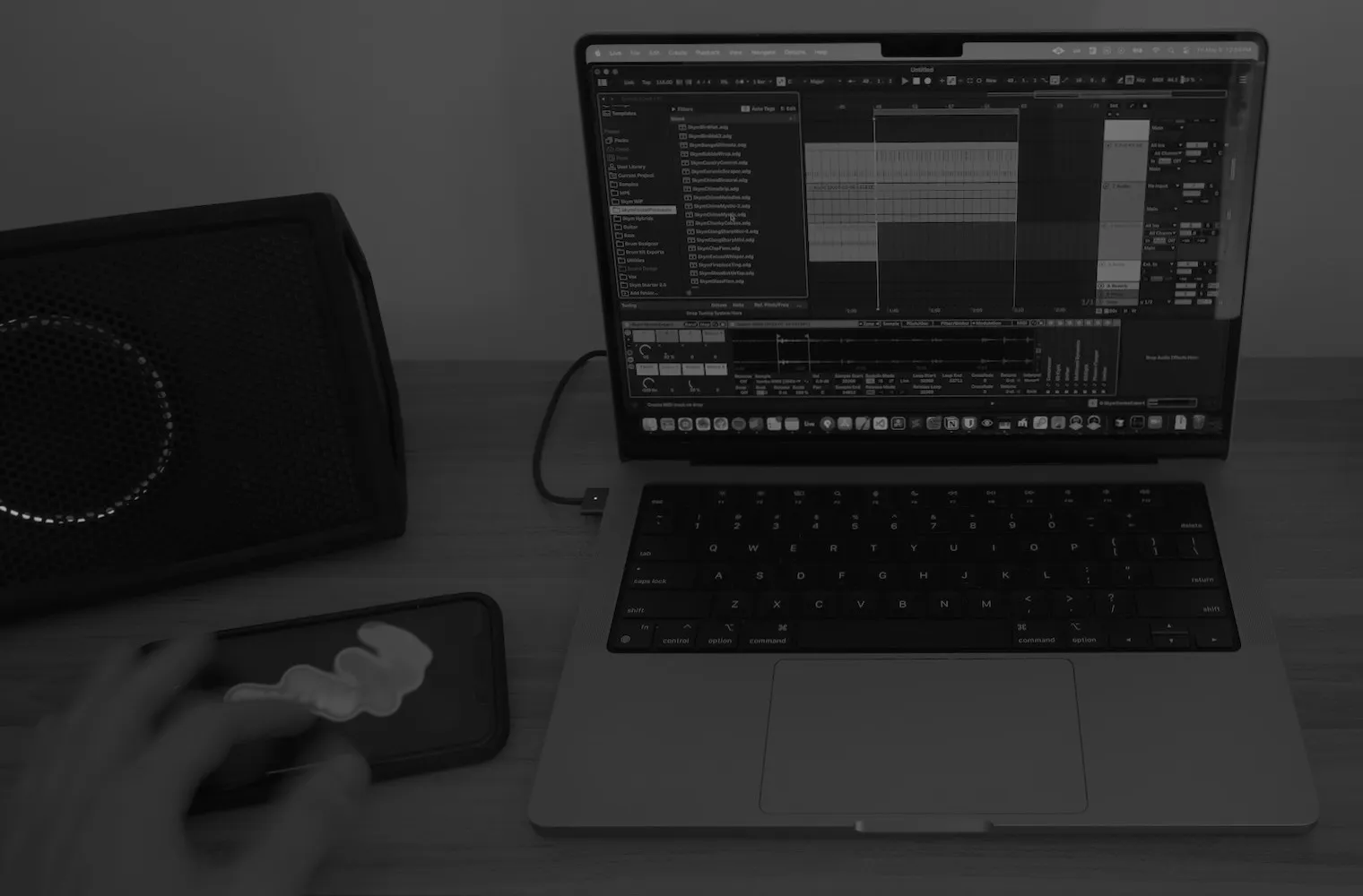 A hand playing Skym on an iPhone, next to a MacBook running Ableton Live